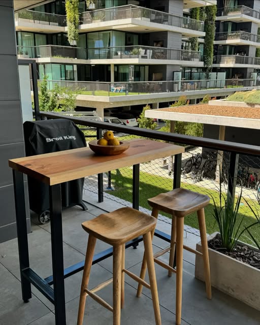 Barra de madera maciza con base de hierro en un balcón, con dos banquetas
